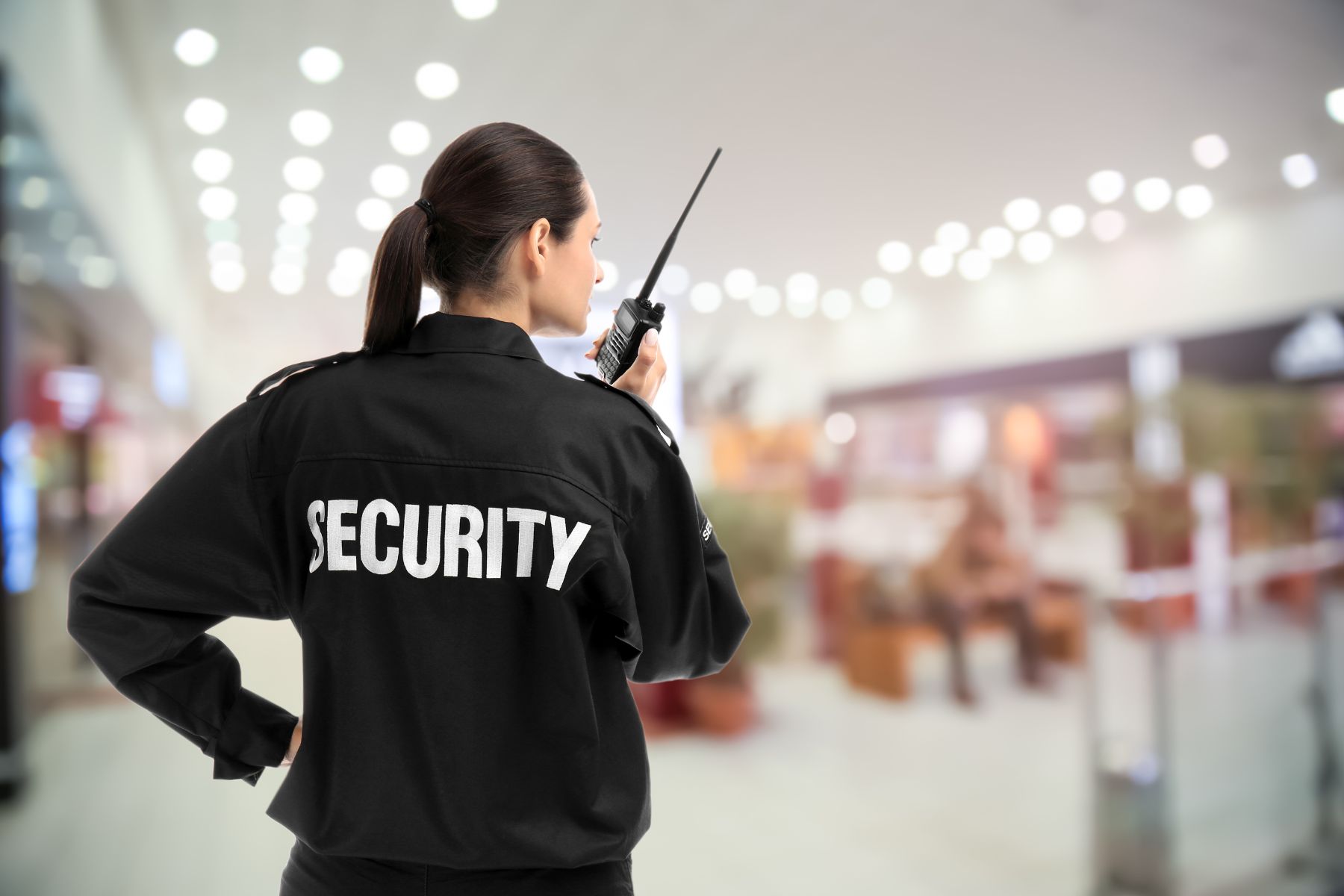 Guardia de seguridad intramuros femenina de Armarium supervisando el acceso a un corporativo en CDMX mediante radiocomunicación.